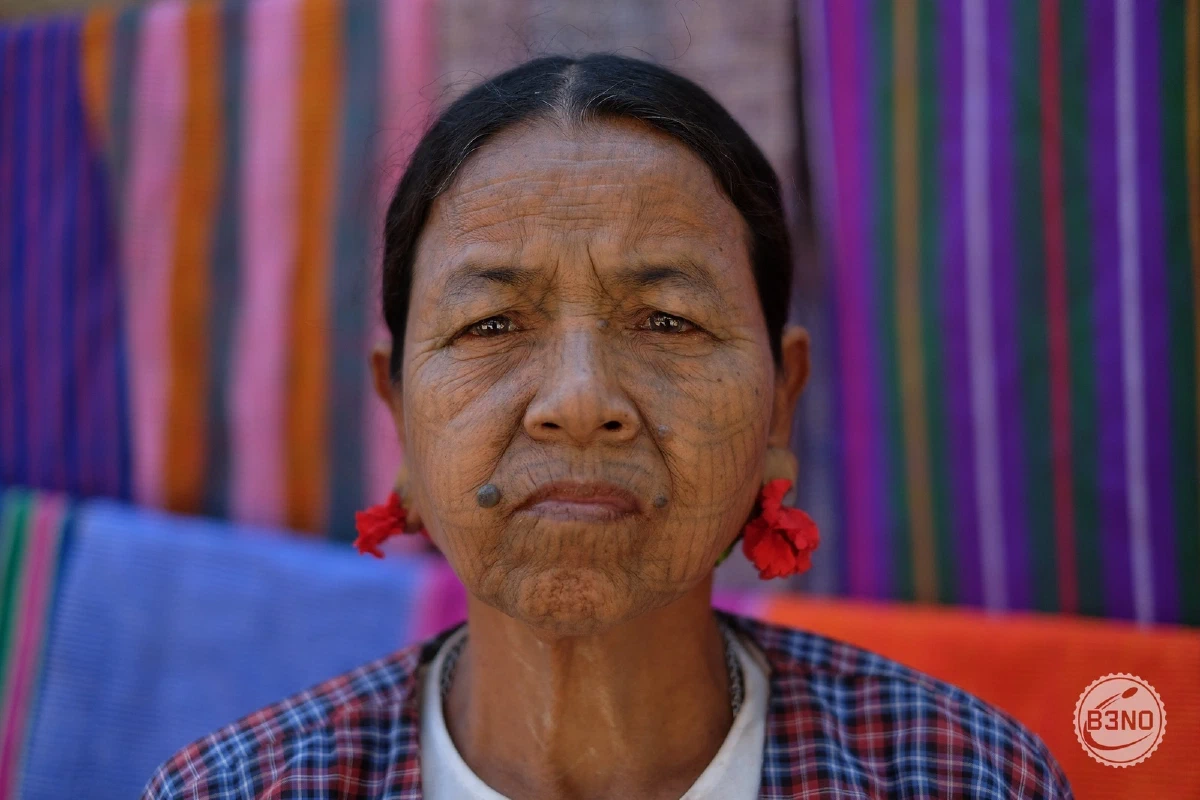 Femme chin au visage tatoué, fleurs rouges aux oreilles, région de Mrauk-U — Mrauk U, Voyages